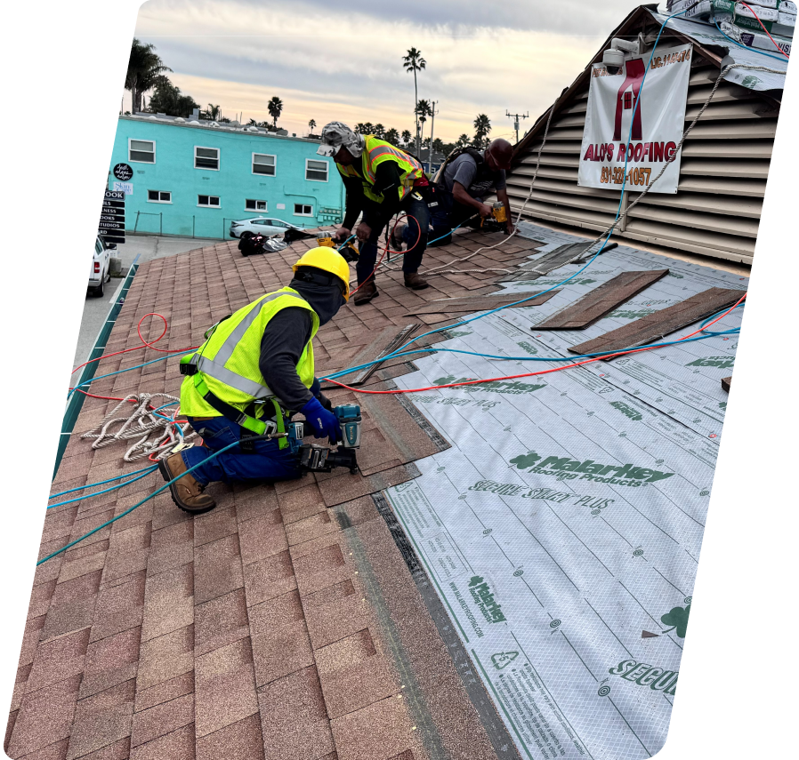 Three Alo's Roofing contractors wearing high-visibility vests and safety harness ropes installing brown shingles over Malarkey Secure Start Plus underlayment during an active residential roof project.