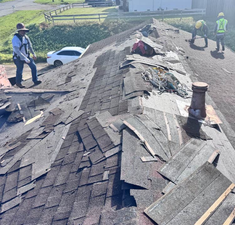 An overhead view of a residential roof replacement in progress, showing exposed wooden decking sheets next to a section of newly installed grey asphalt shingles.