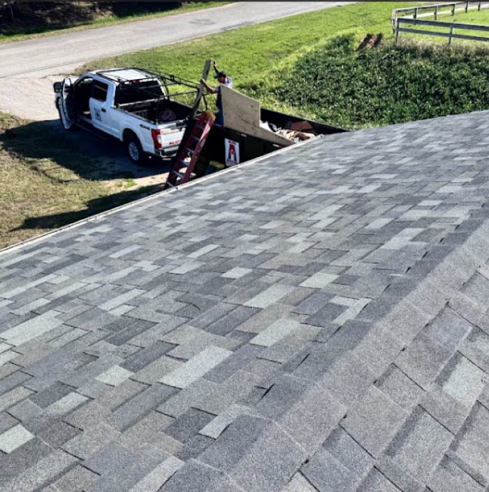 An Alo's Roofing company truck parked on the street with bundles of premium Malarkey Highlander architectural asphalt shingles neatly stacked on the lawn ready for installation.