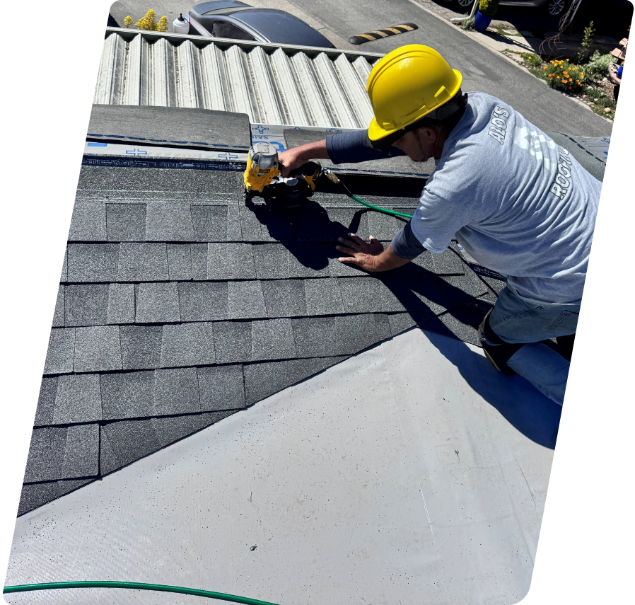 A professional roofer in a yellow hard hat and branded grey shirt carefully laying shingles over a DiamondDeck underlayment base.