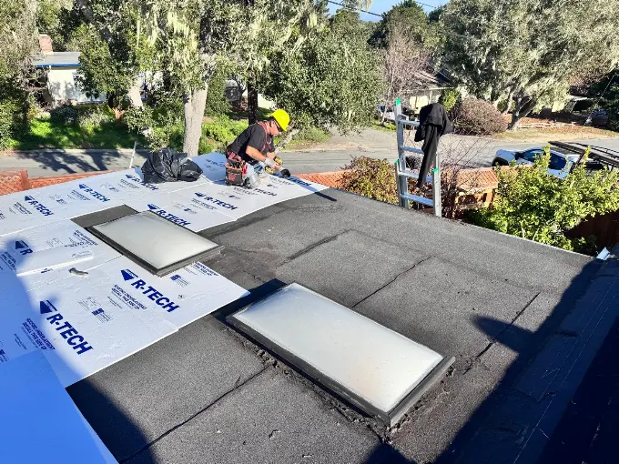 Alo's Roofing contractor installing R-Tech insulation panels over a flat roof with skylights in Watsonville, CA